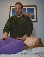 Reiki Master Jon Rosenberg holds his hands close the head of his wife Lisa to a treatment designed to release a person's energy.